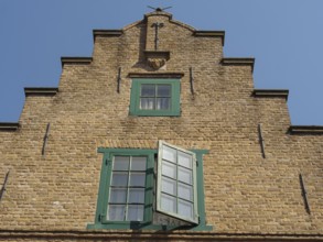 Historic brick building with green framed windows and blue sky, friedrichstadt, schleswig-holstein,
