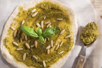 Preparation of uncooked pizza with pesto sauce