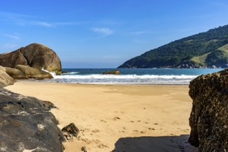 Bonete Beach on the island of Ilhabela seen through the rocks in the sand