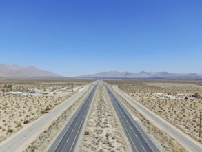 Aerial view of road in the middle of the desert under blue sky in California's Mojave desert, near