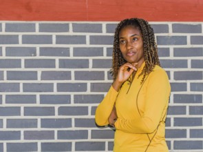 Young black woman in yellow with curly hair posing against a brick wall, Taken in Daejeon, South