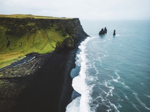 Volcanic Black Sand Beach with a view of Reynisdrangar. Waves crashing on the black sand beach.