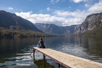 Sitting on a small jetty and enjoying the view on the landscape of lake Bohinj in the Triglav