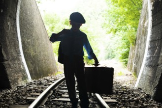 Child walking on railway road with vintage siutcase