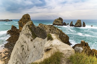 Picturesque cliffs and huge stones oppose the ocean. Spanish coast, Cantabria. Rocky coastline of