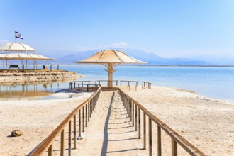 Lovely round umbrella protects from the sun. The drainless salt lake in the Middle East. Dead Sea.