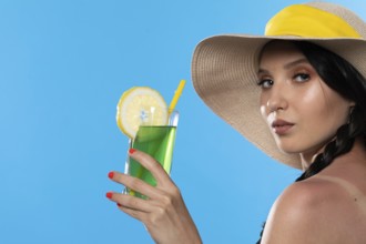 A teenager with an alcoholic drink in her hand and a large hat basks in the summer sun