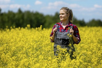 A cheerful and joyful woman happily stands amidst a vast field of vibrant yellow flowers beneath a