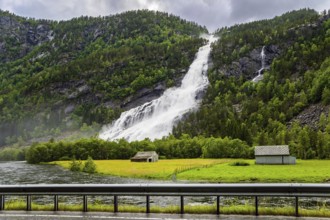 Norway. Huge powerful waterfal Vidfossen. White water foam envelops the foot of the waterfall. Lush