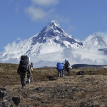 Hiking on Kamchatka Peninsula: group of tourists and travelers with backpacks behind the shoulders