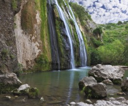 Three parallel streams of water running down the steep slope and fall in oval pool. Three-jet