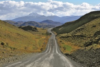 A gravel road winds among the hills and mountains. Chilean Patagonia. Summer in the national park