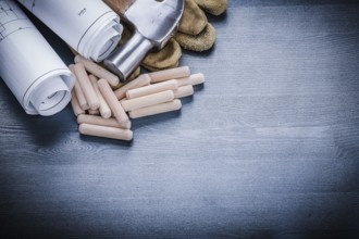 Rolled blueprints hammer gloves wooden dowels