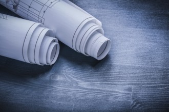Rolled white blueprints on wood board