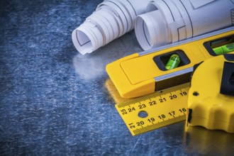 Ruler measuring tape construction level and blueprints on metallic scratched background building