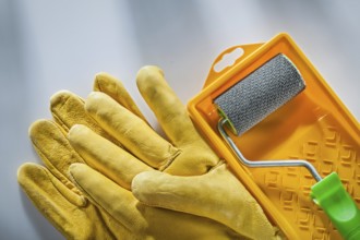Leather safety gloves paint tray roller on white surface