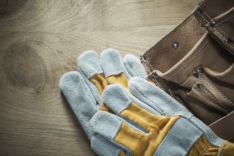 Leather building belt safety gloves on wooden board