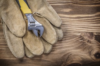 Safety gloves adjustable wrench on wooden board construction concept