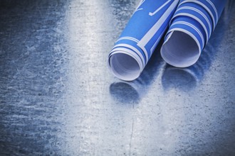 Stack of blue construction plans on metallic background building concept
