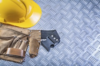 Tool belt building helmet on grooved metal plate construction concept