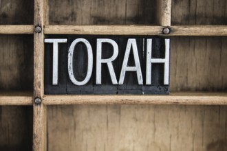 The word TORAH written in vintage metal letterpress type in a wooden drawer with dividers
