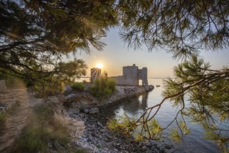 Sunrise on a rocky coast. Reflection in the calm water. Landscape shot of the restored remains of