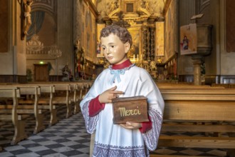 Altar boy sculpture with Merci donation box for the collection in the Catholic Cathedral Notre-Dame