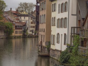 Historic houses with shutters along a quiet canal on a cloudy day, strasbourg, france