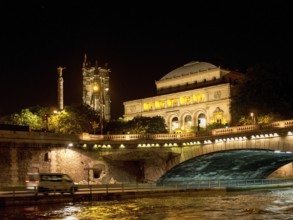Illuminated bridge and historic building at night, reflected in the water of the river, paris,
