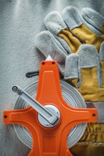 Pair of protective gloves measuring tape on concrete background