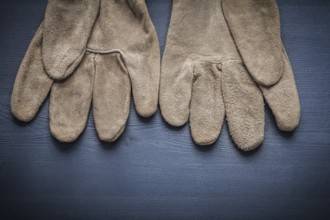 Pair of protective working gloves on wooden board