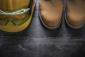 Protective goggles hard hat safety boots on wood board