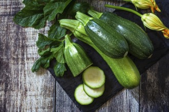 Harvesting zucchini. Healthy uncooked fresh green zucchini with slice on a wooden kitchen table.