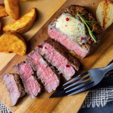 Rustic medium rare beef steak with herbs and potato wedges