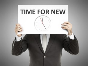 A business man holding a paper in front of his face with time for new and a clock