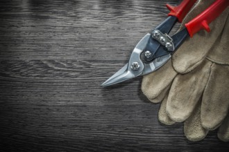Pair of protective gloves steel cutter on wooden board