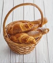 View baguettes and croissants in wicker basket on white boards