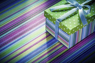 Wrapped cardboard box with gift on striped tablecloth celebrations concept
