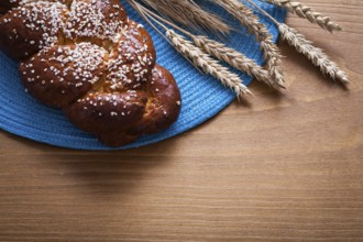 Fresh-baked bun wheat rye ears with blue wattled cover on wooden board food and drink concept