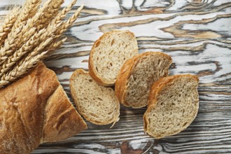 Sliced bread ripe rye ears on wooden surface