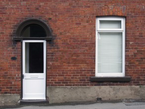 White front door and window of a typical old brick british terraced house with white windows and