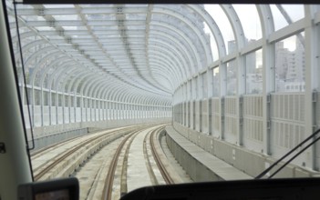 A light rail train moves through an above ground tunnel