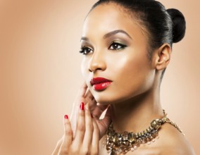 Upscale Indian woman wearing gold jewellery and red lipstick on beige background, Toronto, Canada