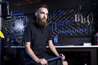 Portrait of small business owner of young man with beard. Guy bicycle mechanic workshop worker