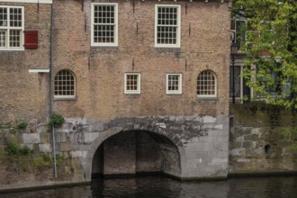 Brick wall with several windows and a large arch leading into the water, Rotterdam, Netherlands