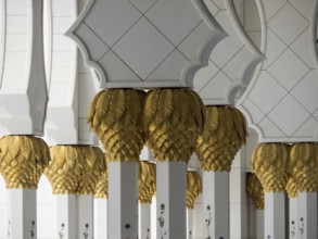 Decorative white columns with golden ornaments in a mosque, detail view, white mosque with towers