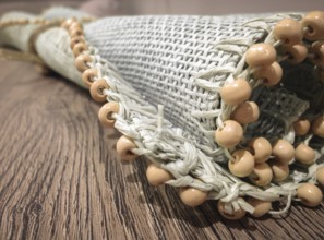 Small roller wicker mat on vintage table. Furnishing accessory for home. Close-up