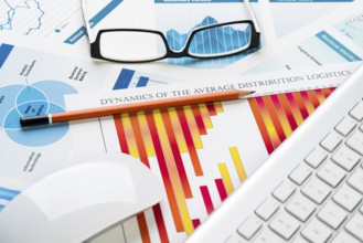 Business workplace with keyboard glasses and financial documents on table
