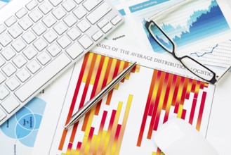 Business workplace with keyboard glasses and financial documents on table
