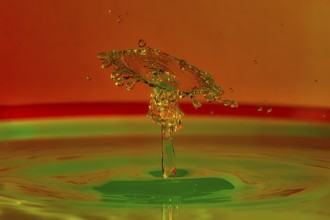 Close-up of a coloured water splash with green and orange that looks like a plastic sculpture,